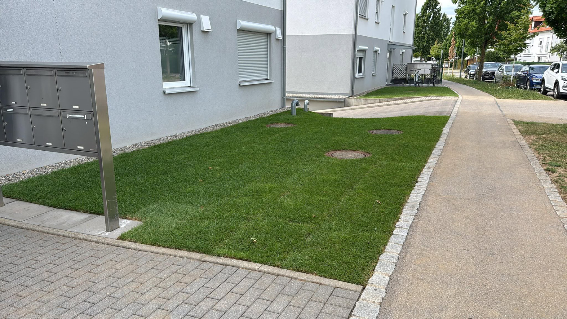 Gepflegte Rasenfläche entlang eines Gebäudes mit Pflasterweg im Donau-Ries